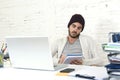 Trendy businessman in cool hipster beanie writing on pad working in at modern home office with computer Royalty Free Stock Photo