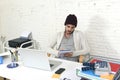 Trendy businessman in cool hipster beanie writing on pad working in at modern home office with computer Royalty Free Stock Photo