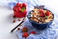 Trendy cereal pancakes in blue bowl with strawberries, hazelnuts and chocolate, spoon on blue gauze on white wooden background Royalty Free Stock Photo