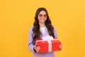 trendy cheerful kid in sunglasses and suit hold gift box on yellow background, shopping Royalty Free Stock Photo