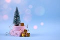 Trendy Christmas and New Year composition with Christmas tree, present boxes, decorations and bokeh lights on pastel blue Royalty Free Stock Photo