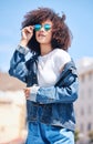 Trendy and cool hispanic woman wearing sunglasses and denim casual clothes while standing outside. Cheerful woman with a