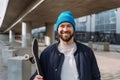 Trendy cool men portrait took to the camera, holding skate board and wearing cap. Skateboard spot. Royalty Free Stock Photo