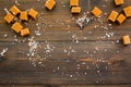 Trendy dessert. Salted caramel. Caramel cubes sprinkled by salt crystals on dark wooden background top view space for Royalty Free Stock Photo