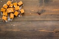 Trendy dessert. Salted caramel. Caramel cubes sprinkled by salt crystals on dark wooden background top view space for Royalty Free Stock Photo