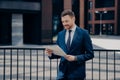 Trendy dressed businessman in stylish clothing reading business news outdoor Royalty Free Stock Photo