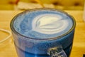 Trendy drink: Blue latte. Top view of hot classic blue color butterfly pea latte tea or blue spirulina latte on wood textured