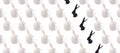 Trendy Easter pattern made of white rabbits hares toys and row of black bunnies on white isometric background in minimal geometry