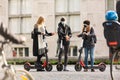Trendy fashinable group of friends riding public rental electric scooters in urban city environment at fall. New eco Royalty Free Stock Photo