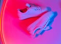 Trendy fashion white sneakers on abstract bright background. Neon lights on casual shoes. Violet and red gradient light. Royalty Free Stock Photo