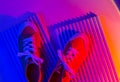 Trendy fashion white sneakers on geometry podium on abstract bright background. Neon lights on casual shoes. Violet and red Royalty Free Stock Photo