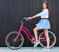 Trendy Fashionable Girl with Vintage Bike on Black Wooden Background. Toned Photo. Modern Youth Lifestyle Concept.