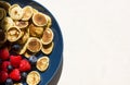 Trendy food - tiny pancake cereal. Heap of mini cereal pancakes with raspberries and blueberries in blue plate on white background Royalty Free Stock Photo