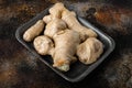 Trendy food whole ginger root, in plastic market  container, on old dark rustic background Royalty Free Stock Photo