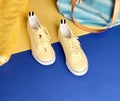 Footwear for women yellow sneakers towel and handbag for relaxation time on blue and yellow background