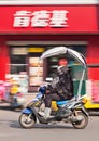 Trendy girl on an e-bike passes KFC outlet, Hengdian, China