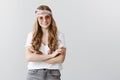 Trendy girl likes express herself with clothes. Happy pleased woman in trendy headband and sunglasses holding crossed