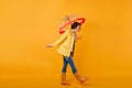 Trendy girl in rubber shoes and yellow jacket looking down while posing with umbrella. Studio shot of curly short-haired Royalty Free Stock Photo