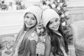 Trendy girls. Winter season accessory. Children wear knitted hats. Girls long hair happy smiling faces christmas tree Royalty Free Stock Photo