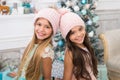 Trendy girls. Winter season accessory. Children wear knitted hats. Girls long hair happy smiling faces christmas tree