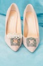 Trendy, graceful suede high heel shoes and wedding rings and jewelery in a blue suede chair. Wedding details.
