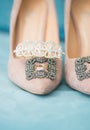 Trendy, graceful suede high heel shoes and wedding rings and jewelery in a blue suede chair. Wedding details.