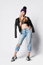 Glamorous brutal style girl in torn jeans, leather top, leather jacket and brutal silver boots is standing thinking Royalty Free Stock Photo