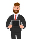 Trendy happy young bearded business man showing/holding blank screen of digital tablet computer in hands. Modern technology.