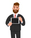 Trendy, happy young bearded business man showing/holding blank screen of digital tablet computer in hands. Modern technology.