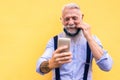 Trendy hipster man using mobile phone doing video call while wearing fashion silk safety mask - Outfit, technology and lifestyle Royalty Free Stock Photo