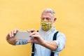 Trendy hipster man using mobile phone doing video call while wearing fashion silk safety mask - Outfit, technology and lifestyle Royalty Free Stock Photo