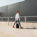 Trendy hipster young man in sunglasses in fashionable summer clothes with cloth bag in vintage sandals walks on the street Royalty Free Stock Photo