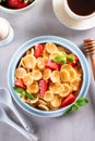 Trendy home breakfast with tiny cereal pancakes with honey and strawberries in the bowl. Top view Royalty Free Stock Photo