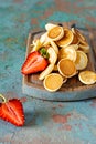 Trendy home breakfast with tiny pancakes mini pancakes with strawberries and mint on a wooden board on a dark background. Royalty Free Stock Photo