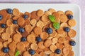 Trendy homemade breakfast, pancake cereal, mini pancakes on light plate on pink concrete background