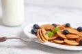 Trendy homemade breakfast, pancake cereal, mini pancakes on white plate on white concrete background with spoon and blueberry, Royalty Free Stock Photo