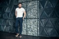 Trendy look. Full length of handsome young man looking away and keeping hands in pockets while standing against grey background