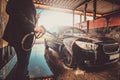 Trendy man in jeans and blaser is washing his own car at car washing station. Royalty Free Stock Photo