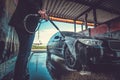 Trendy man in jeans and blaser is washing his own car at car washing station. Royalty Free Stock Photo