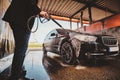 Trendy man in jeans and blaser is washing his own car at car washing station. Royalty Free Stock Photo