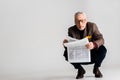 Trendy mature man in glasses holding newspaper while sitting