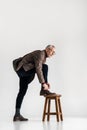 Trendy mature man putting leg on chair while tying shoelaces Royalty Free Stock Photo