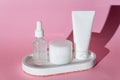 Trendy minimal style presentaion of face care cosmetic products. White unbranded pakage. Mock up fo brands. Hard shados, pink