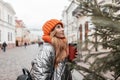 Trendy model of a cute young woman in fashionable youth winter clothes with a leather backpack with a cup of hot tea enjoy a walk Royalty Free Stock Photo