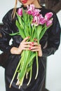 Trendy model in leather black dress and hat with flowers