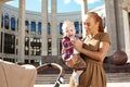 Trendy modern mother on a city street with a pram. Young mother