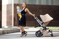 Trendy modern mother on a city street with a pram. Young mother