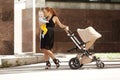 Trendy modern mother on a city street with a pram. Young mother