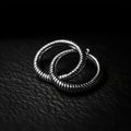 A trendy and modern pair of silver hoop earrings, with a unique spiral design