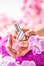 Trendy nail manicure. Woman hands holding nails polishes. Pink decoration from orchids Royalty Free Stock Photo